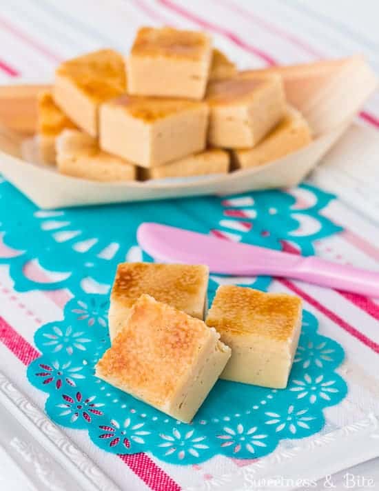 Pieces of crème brulee fudge on a striped background with teal green doilies.