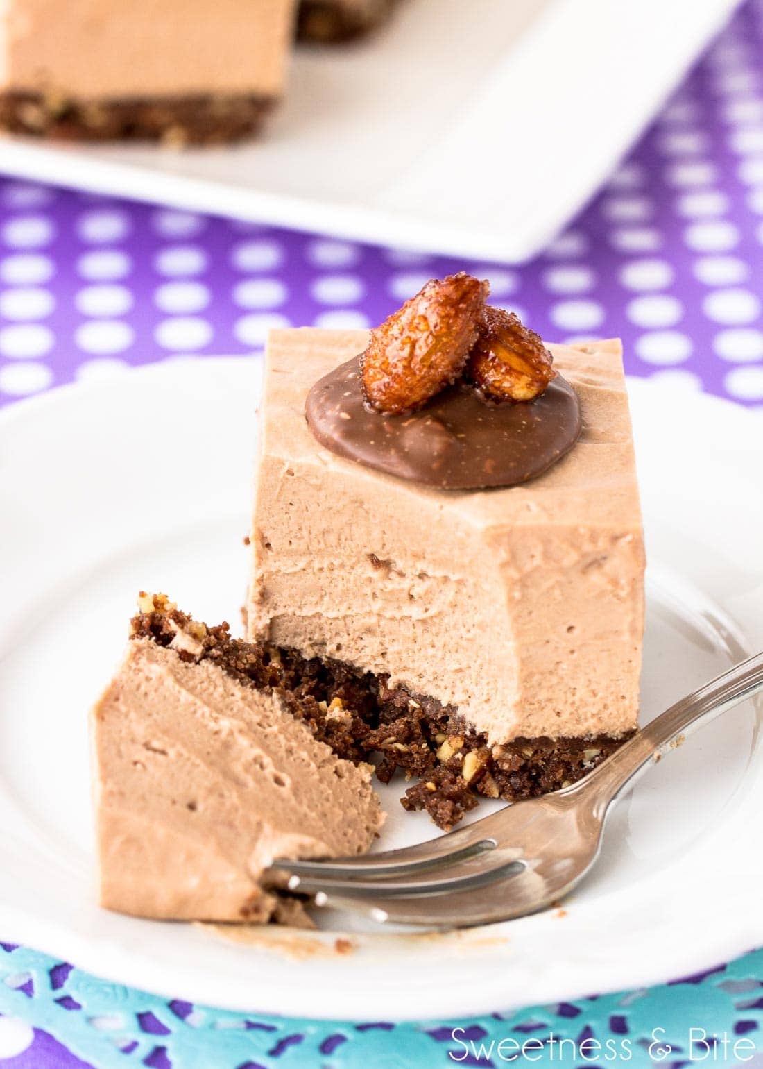 A piece of Toblerone cheesecake that has been cut into with a small dessert fork, on a white plate.