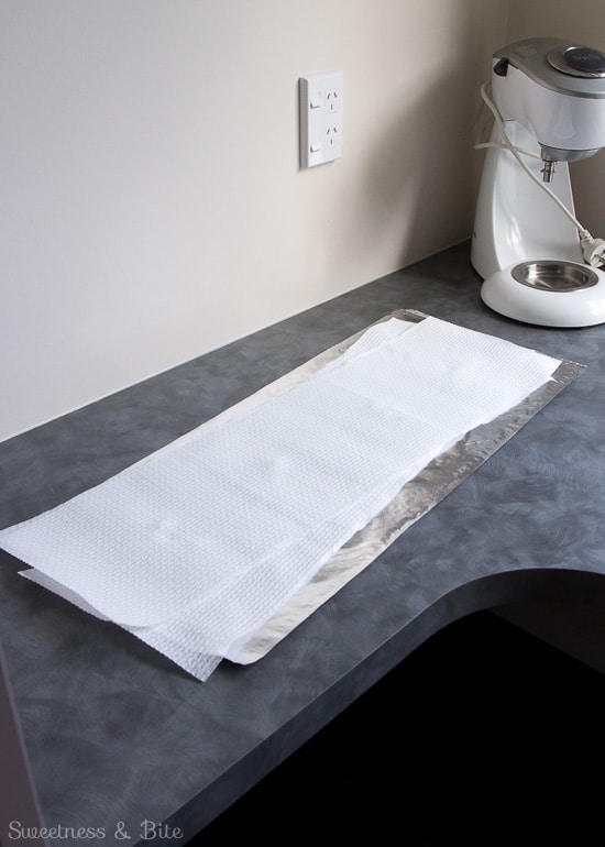 A long strip of foil, with two long strips of paper towels the same length.