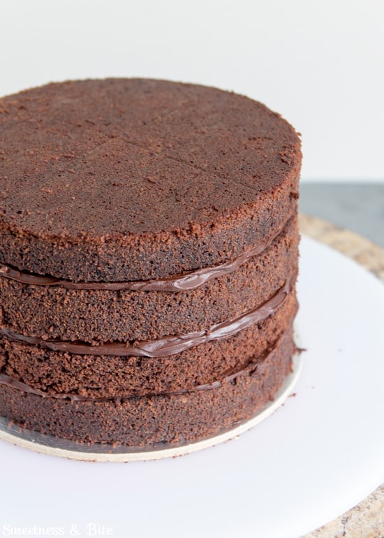 Four stacked cake layers filled with dark chocolate ganache.