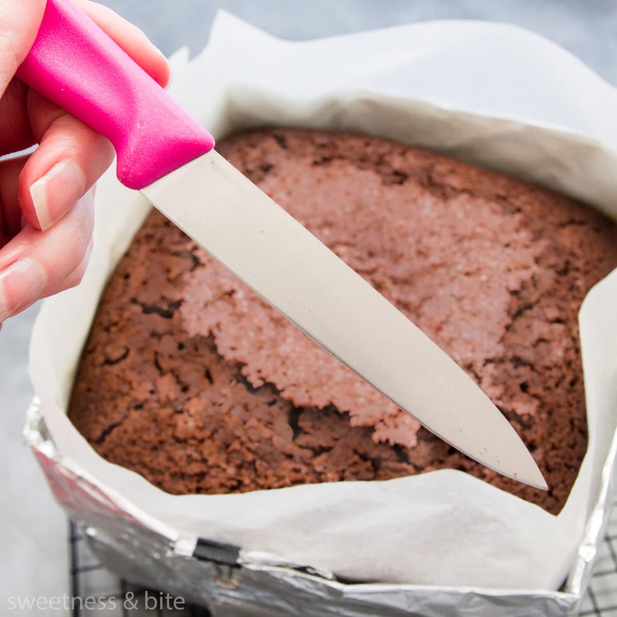 A knife being used to check whether a chocolate cake is done.
