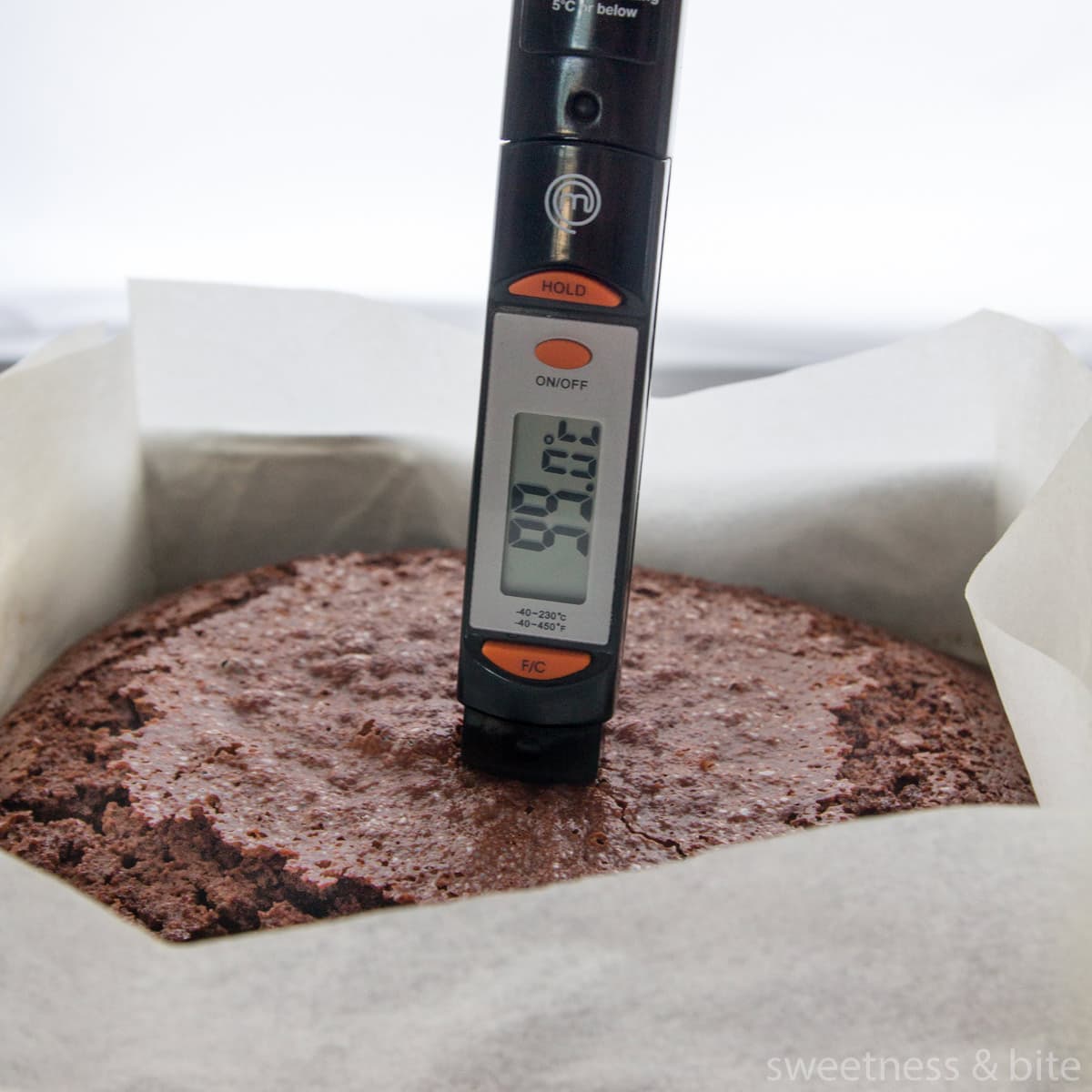 A thermometer being used to check the internal temperature of a cake in Celcius.