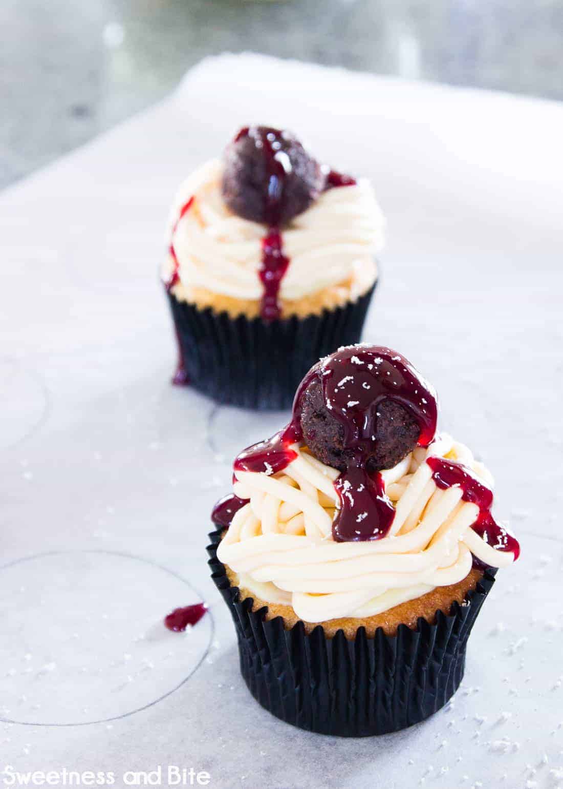 The cupcake finished with a drizzle of berry sauce and sprinkled with grated white chocolate.
