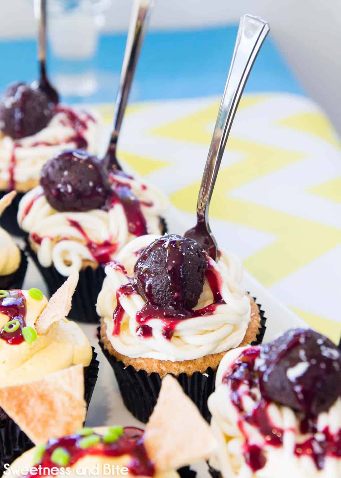 Spaghetti and meatball cupcakes, topped with a small silver plastic fork.