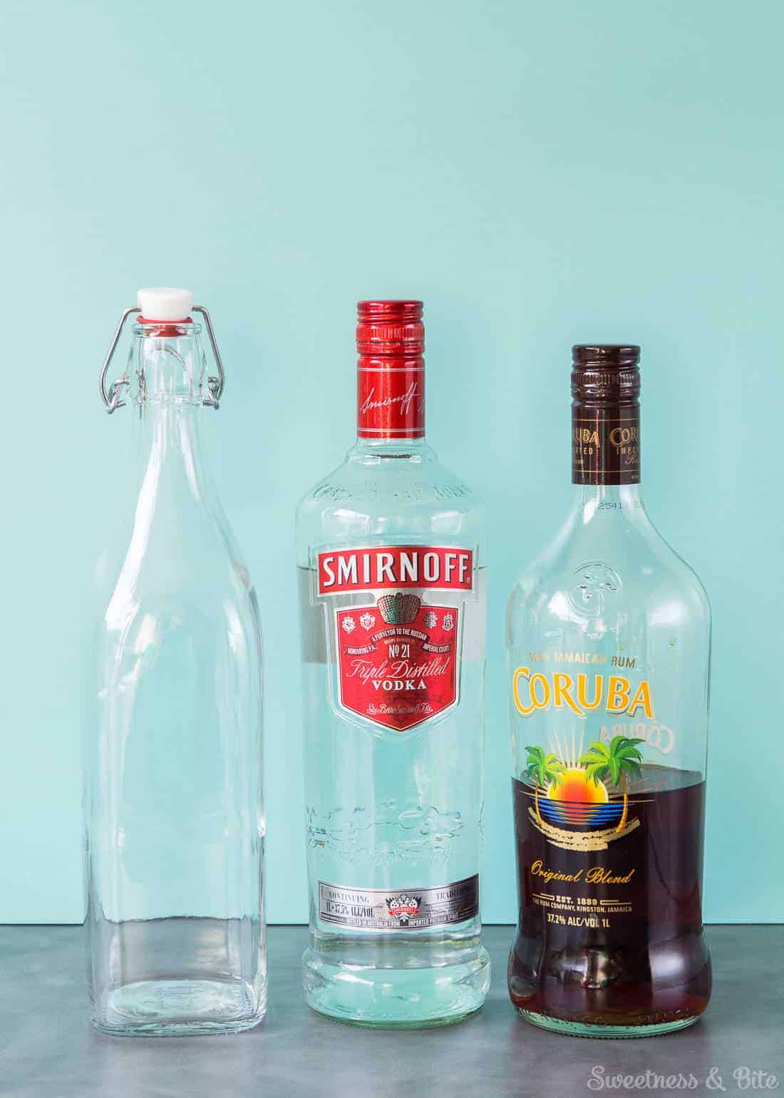 An empty swing-top bottle, a bottle of Smirnoff vodka and a bottle of Coruba rum.