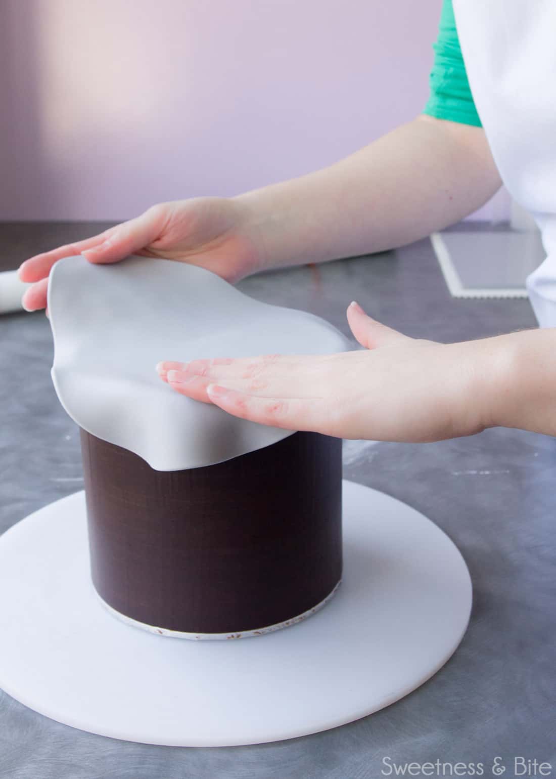 Placing a rolled out circle of fondant onto the top of the cake.