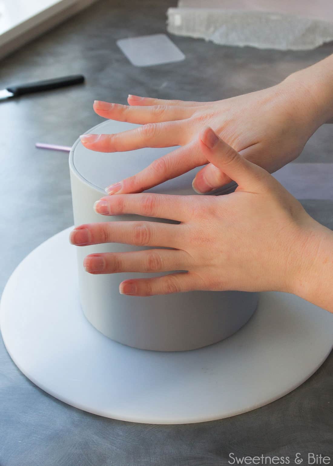 Fingers pressing the fondant along the seam together.