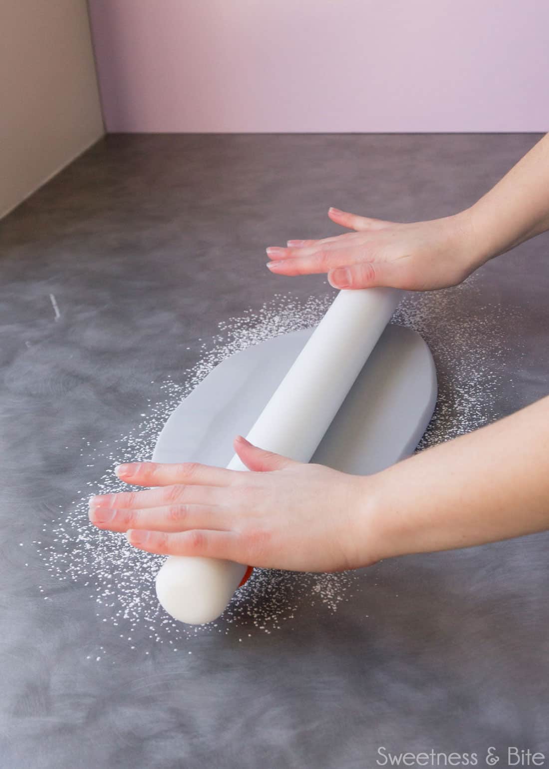 Rolling out the fondant with a long white plastic rolling pin.