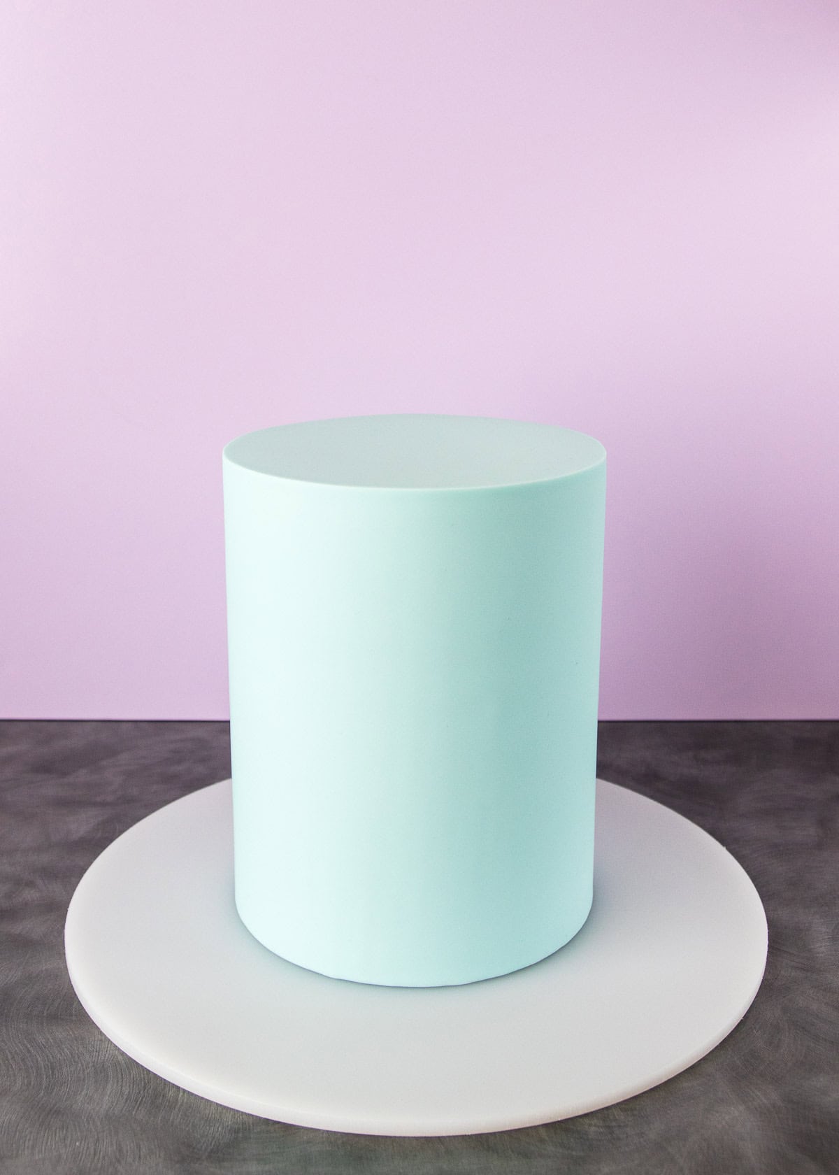 Tall, pale blue fondant covered cake, ready to be painted. 