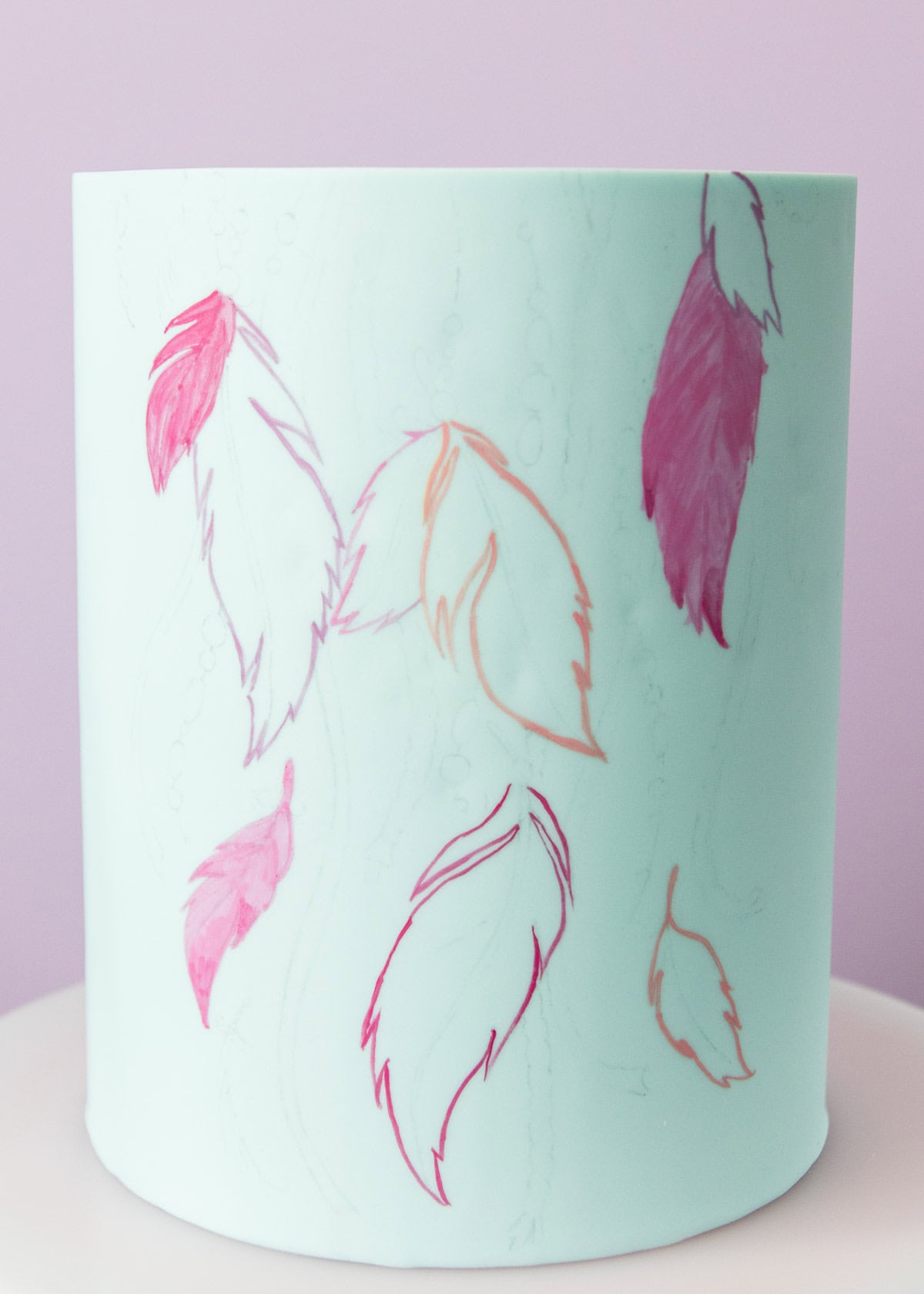 Close up of the feather design being outlined in pink edible paint.