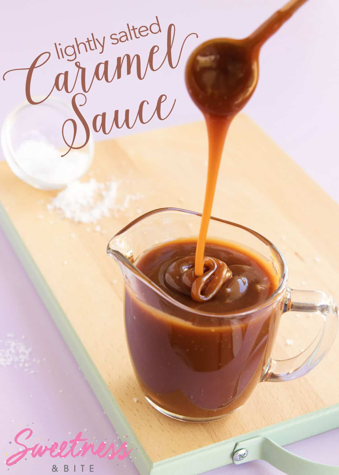 A small round spoon dripping caramel sauce back into a glass jug containing more caramel sauce.