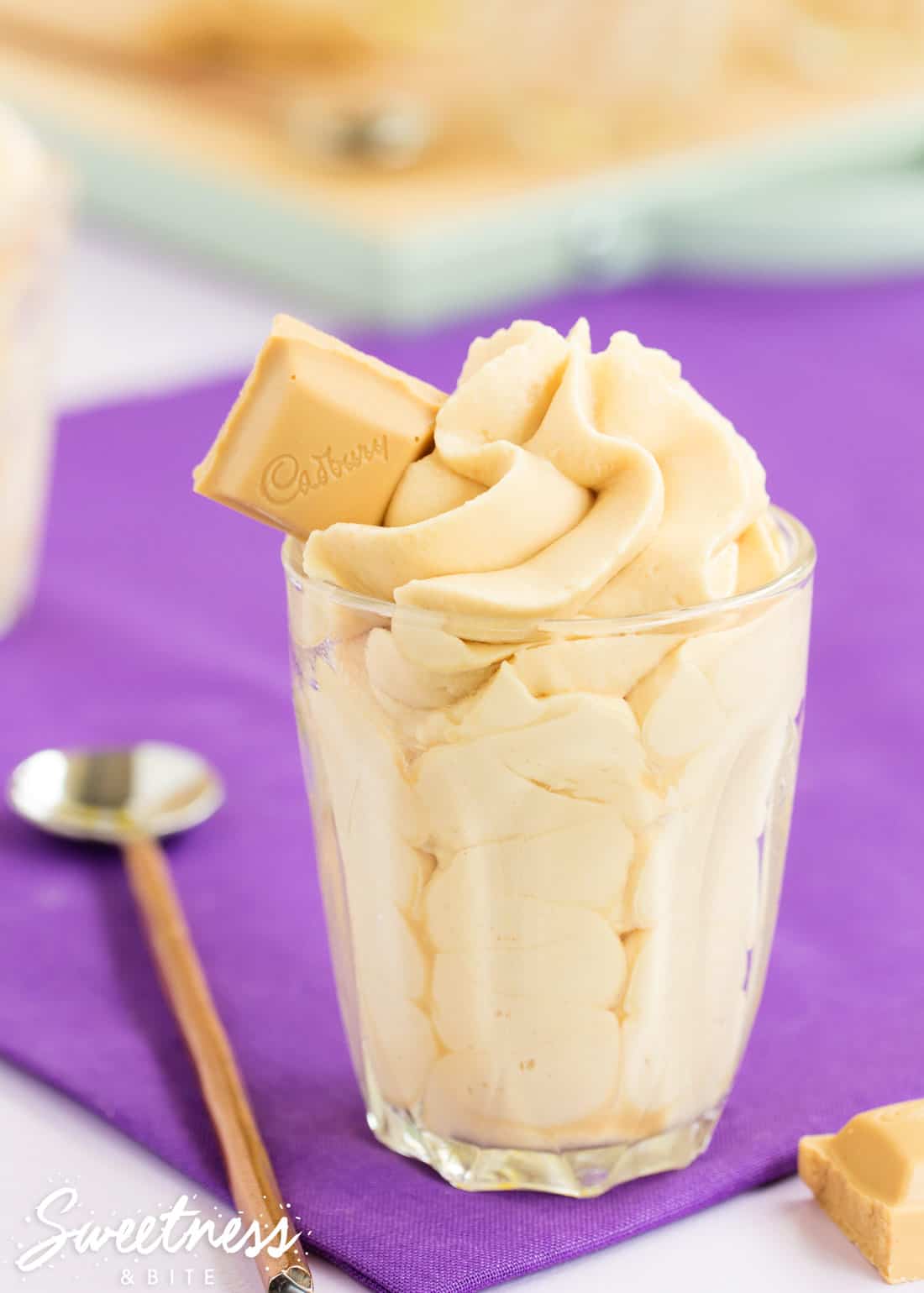 Easy Caramilk Mousse, piped in a swirl into a small glass with a square of Caramilk chocolate on top.