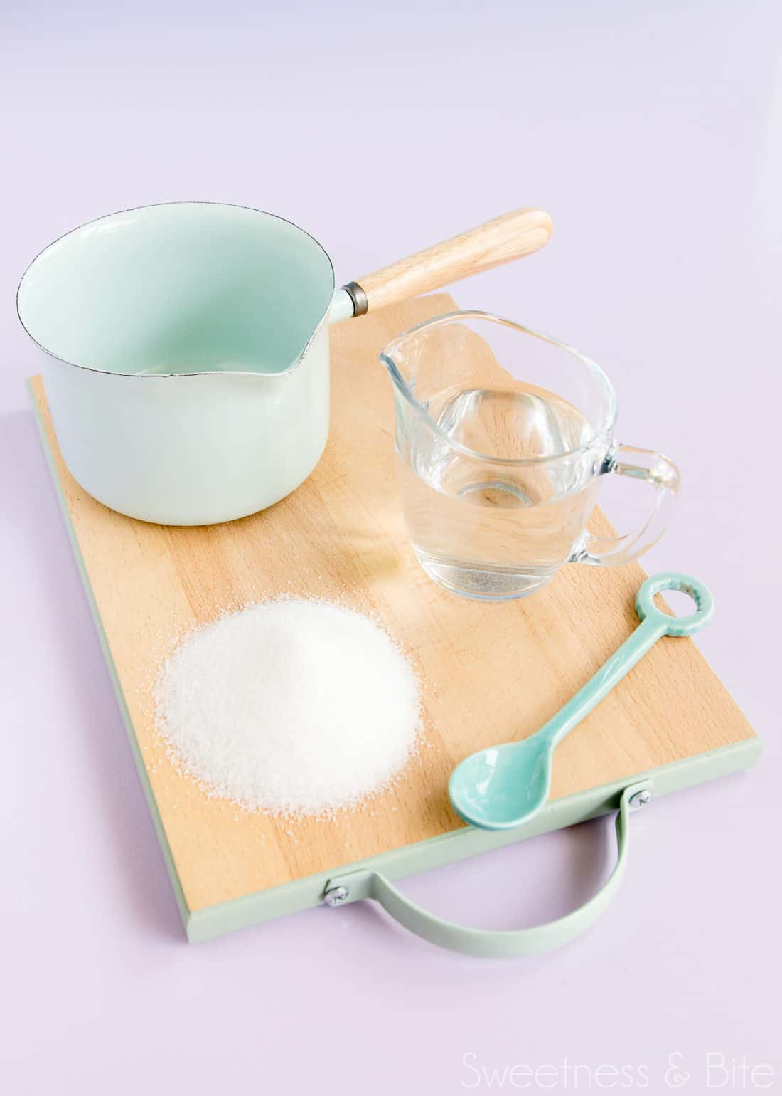 Sugar syrup ingredients and equipment - sugar, water, a small pan and a spoon.