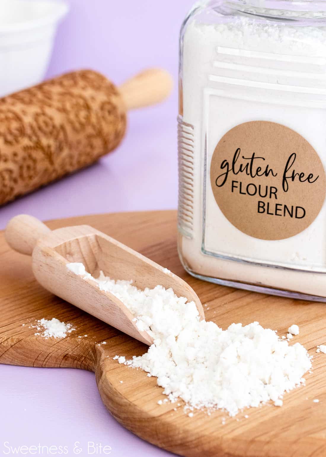 Scoop of gluten free flour blend on a wooden board.