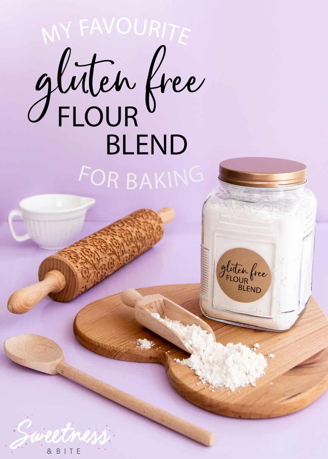 A jar of gluten free flour sitting on a wooden board, on a purple background, with text overlay reading "my favourite gluten free flour blend for baking"