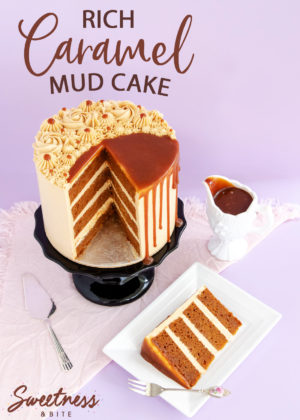 A slice of caramel mud cake filled with caramel buttercream, on a plate, with the rest of the cake in the background on a black cake stand.