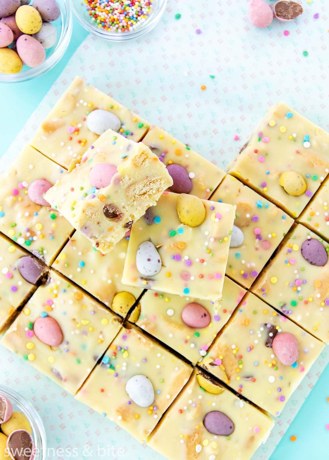 Two squares of mini egg fudge stacked up, showing the cookie pieces inside.