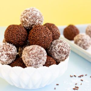 Chocolate coconut truffles stacked in a white milk glass bowl.