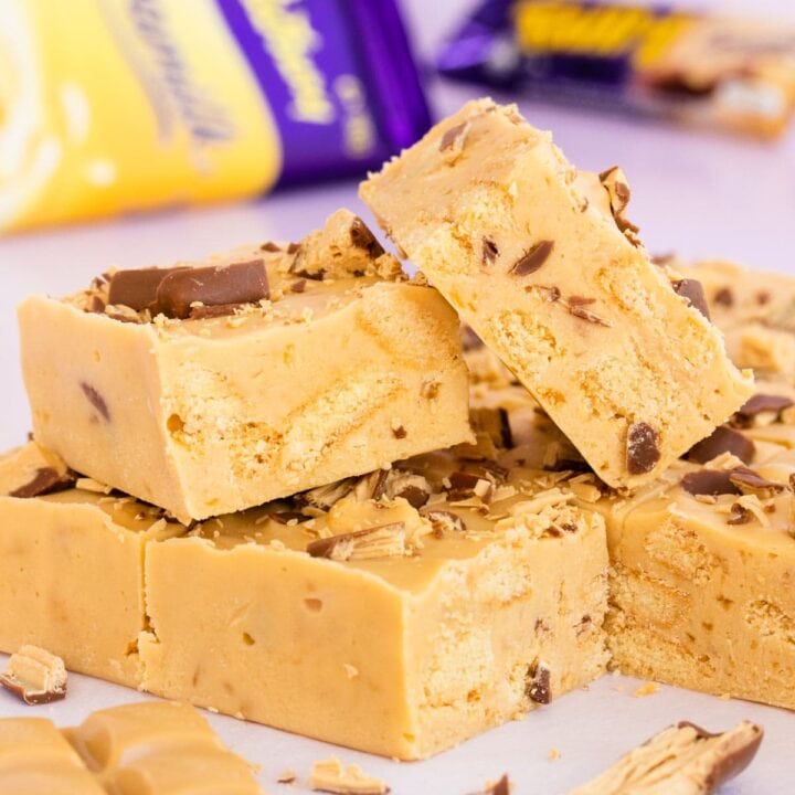 two squares of Caramilk Fudge Slice, stacked on other squares of slice
