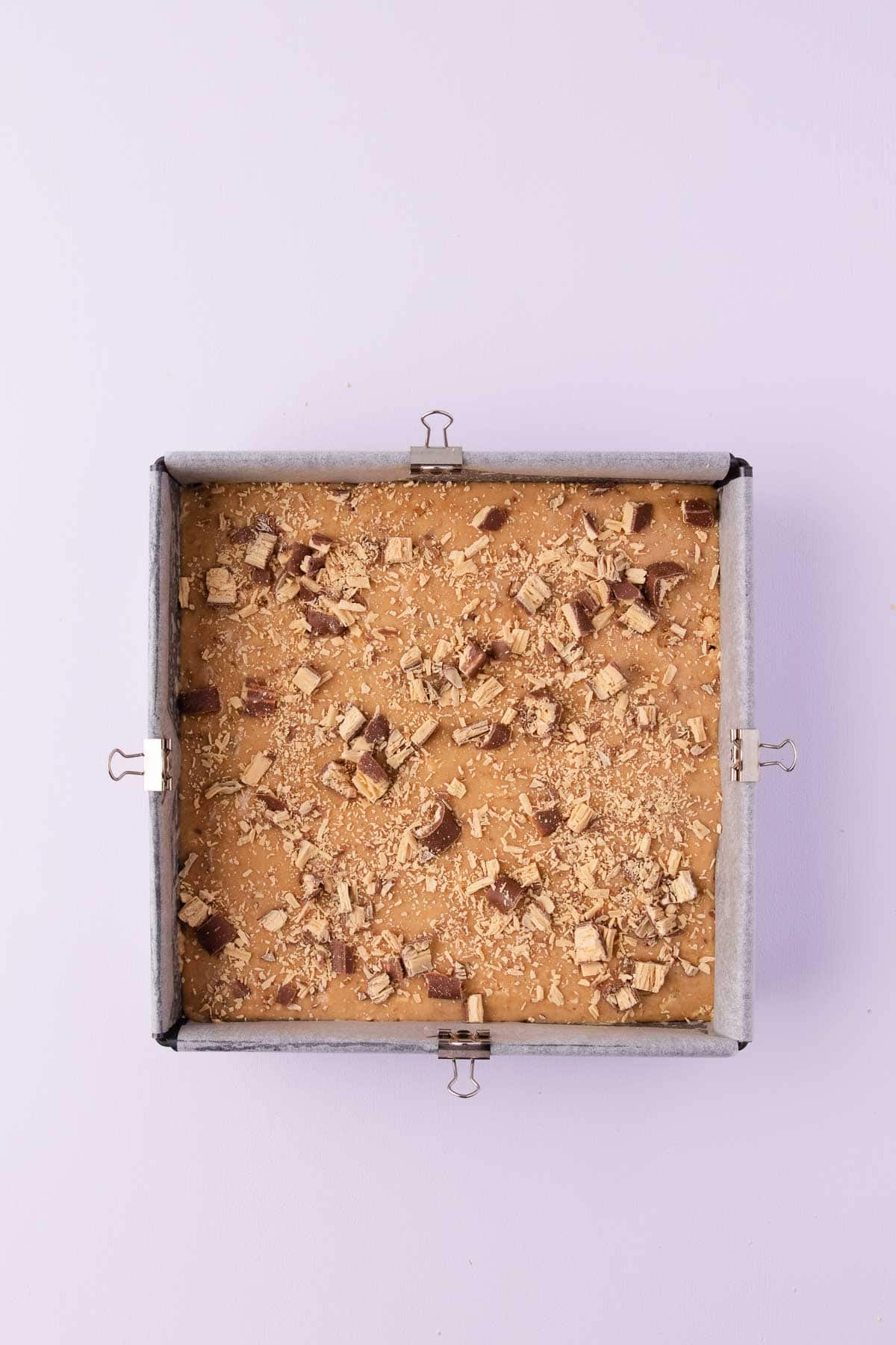 The Caramilk slice mixture pressed into a square cake pan, and sprinkled on top with extra caramilk twirls.