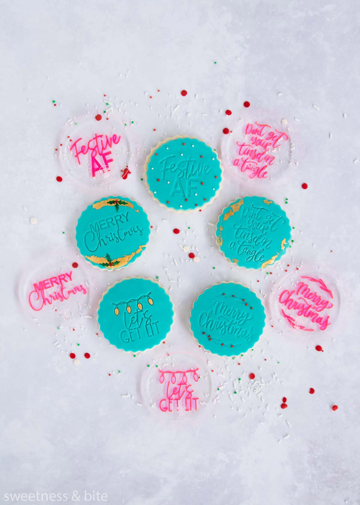 Round cookies decorated with teal fondant circles embossed with messages - Festive AF, Don't get your tinsel in a tangle, Merry Christmas and Let's get lit.