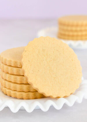 Stack of vanilla cookies on a white glass plate, text overlay reads 