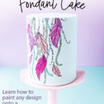 A pale blue fondant-covered cake with a bright dreamcatcher design painted on the front. Text overlay reads: 