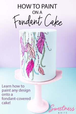 A pale blue fondant-covered cake with a bright dreamcatcher design painted on the front. Text overlay reads: 