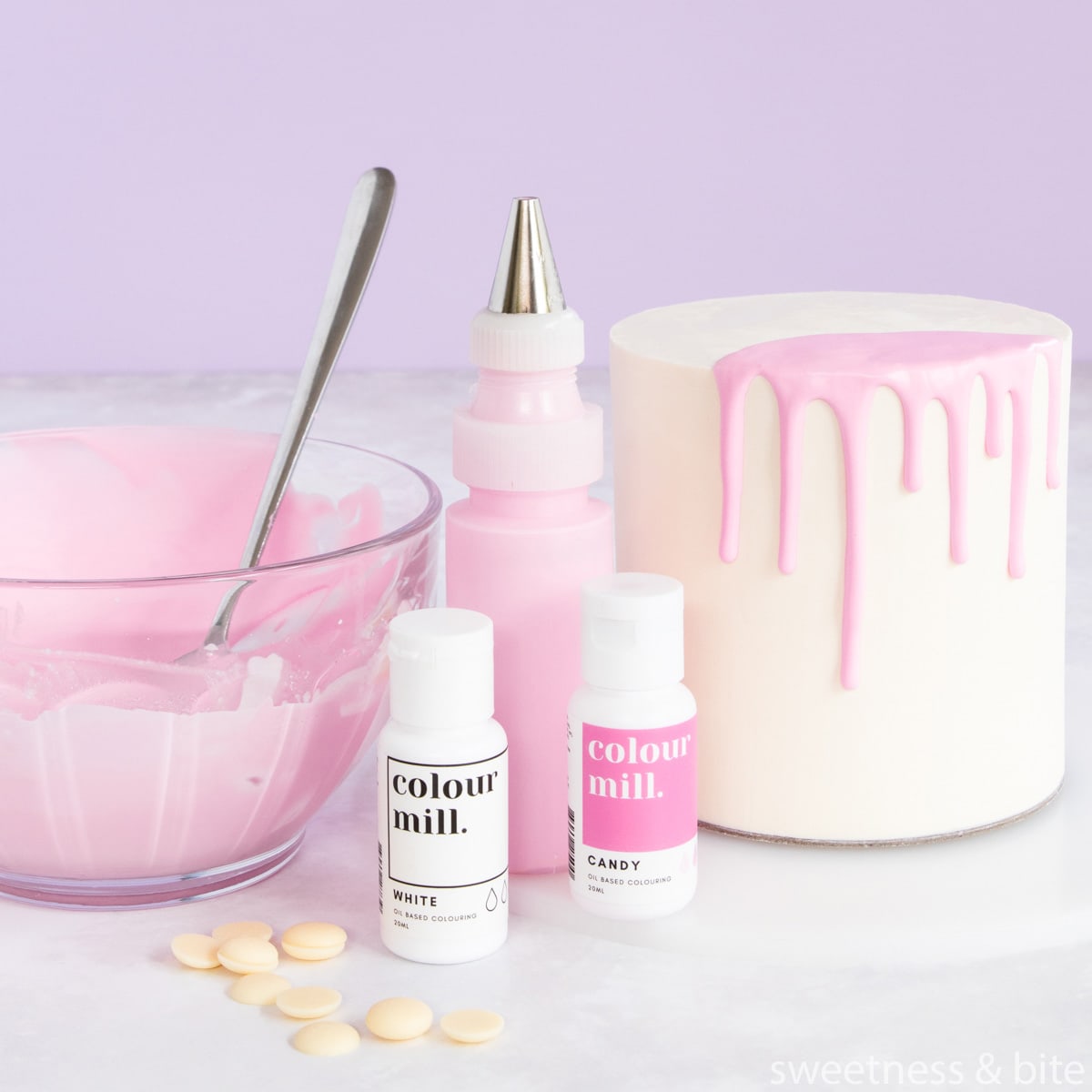Pink ganache in a bowl, a white cake with a pink ganache drip, and two bottles of Colour Mill oil-based food colouring.