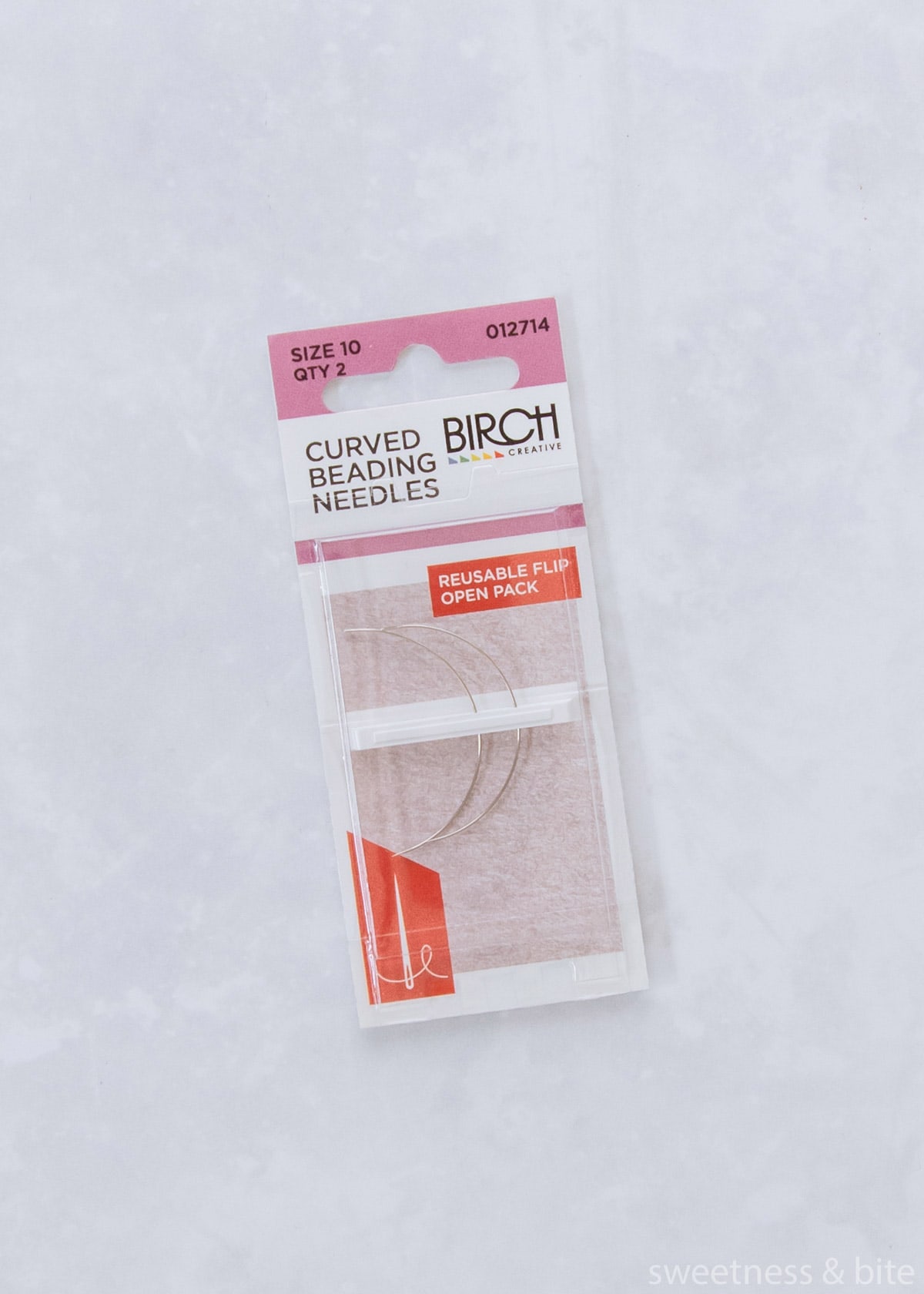 A packet of two curved beading needles.