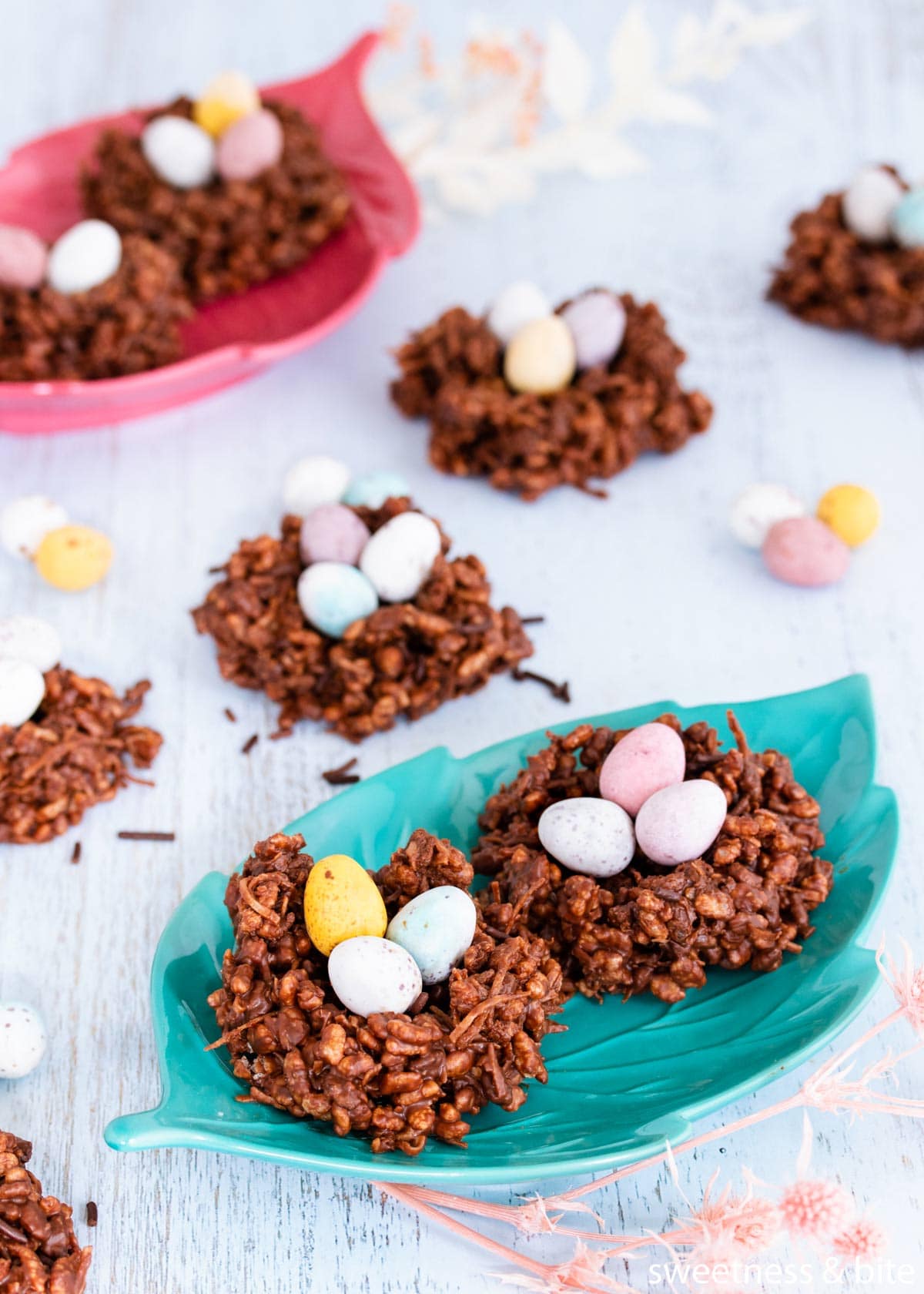 Chocolate Easter nests filled with pastel mini eggs, on a teal green leaf-shaped plate.
