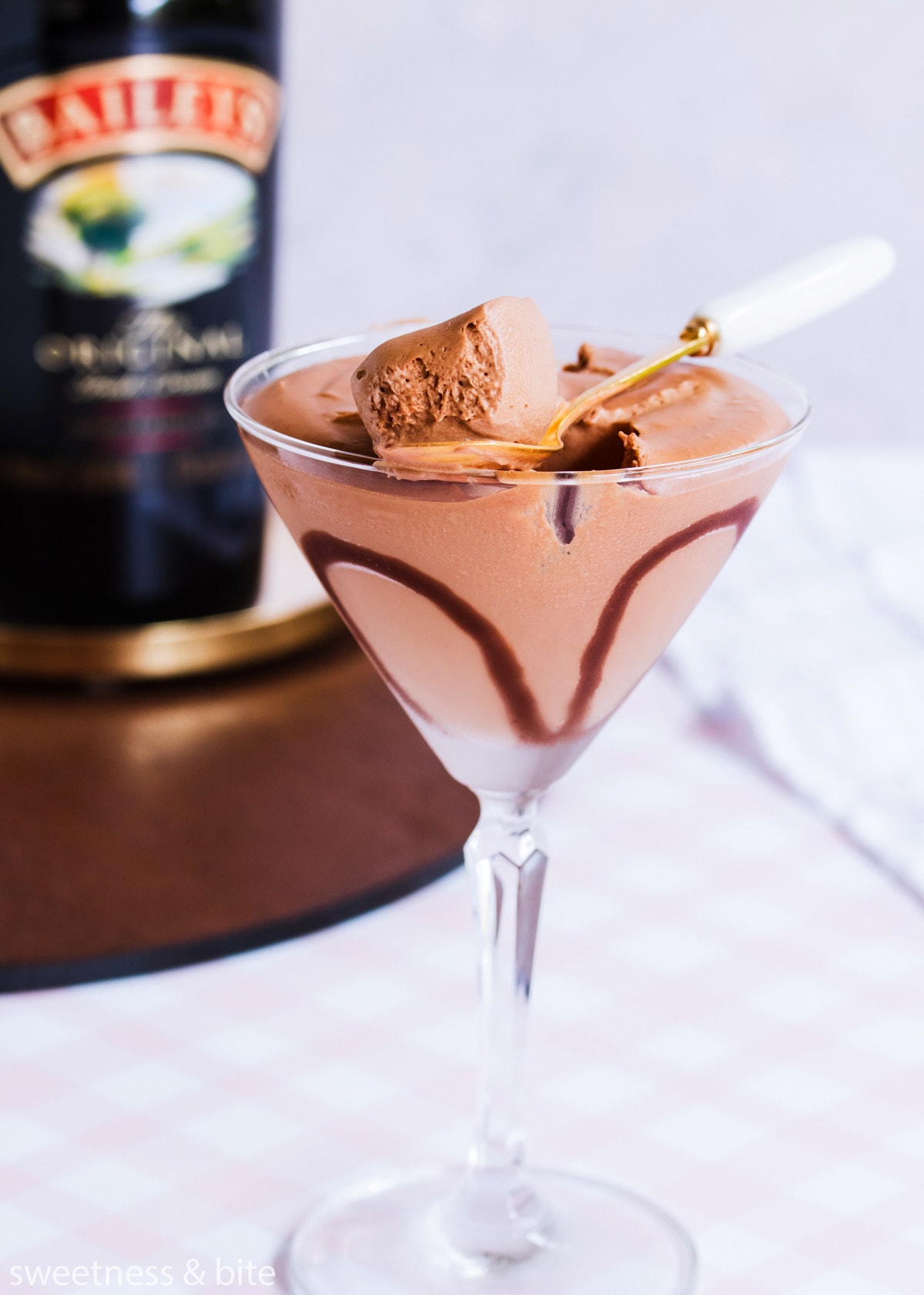 Close up of a spoonful of mousse resting on the edge of a martini glass.