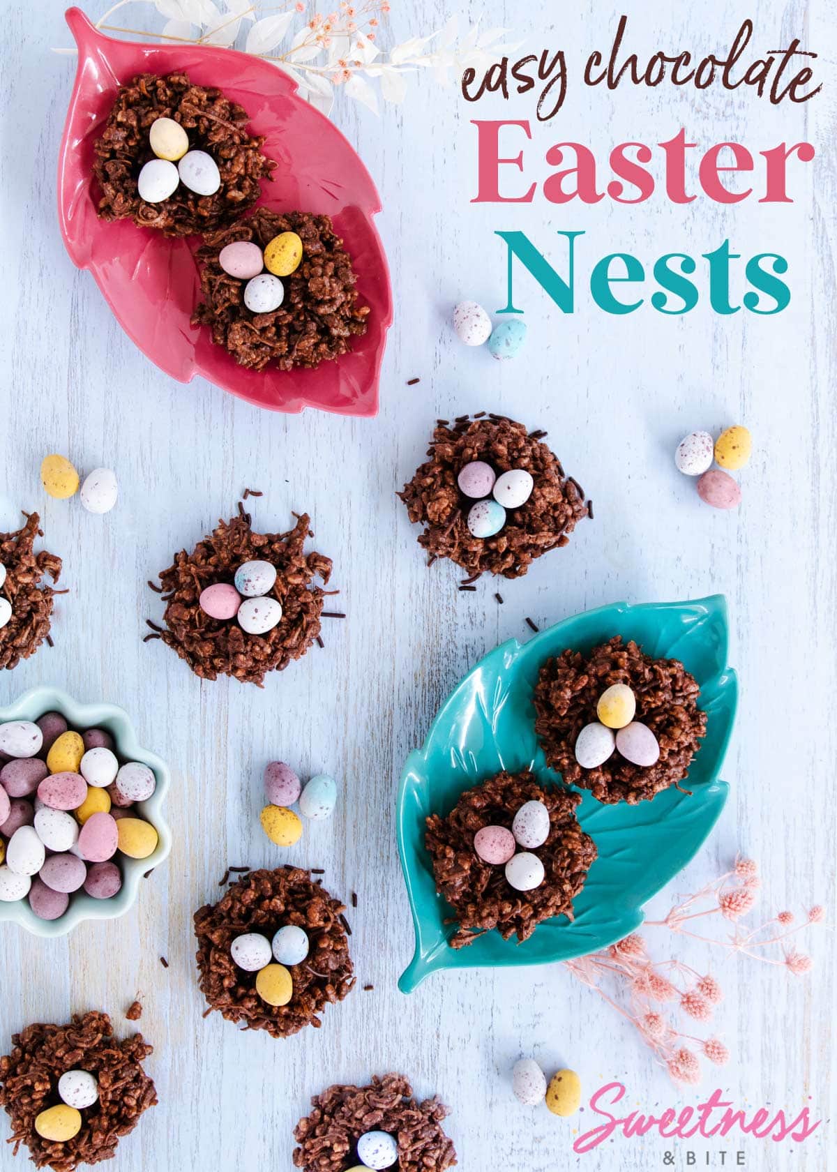 9 chocolate Easter nests, some on leaf-shaped plates, on a blue woodgrain background, surrounded by pastel eggs.