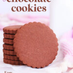Stack of scalloped-edge round gluten free chocolate cookies, with one cookie resting on its side against the stack.