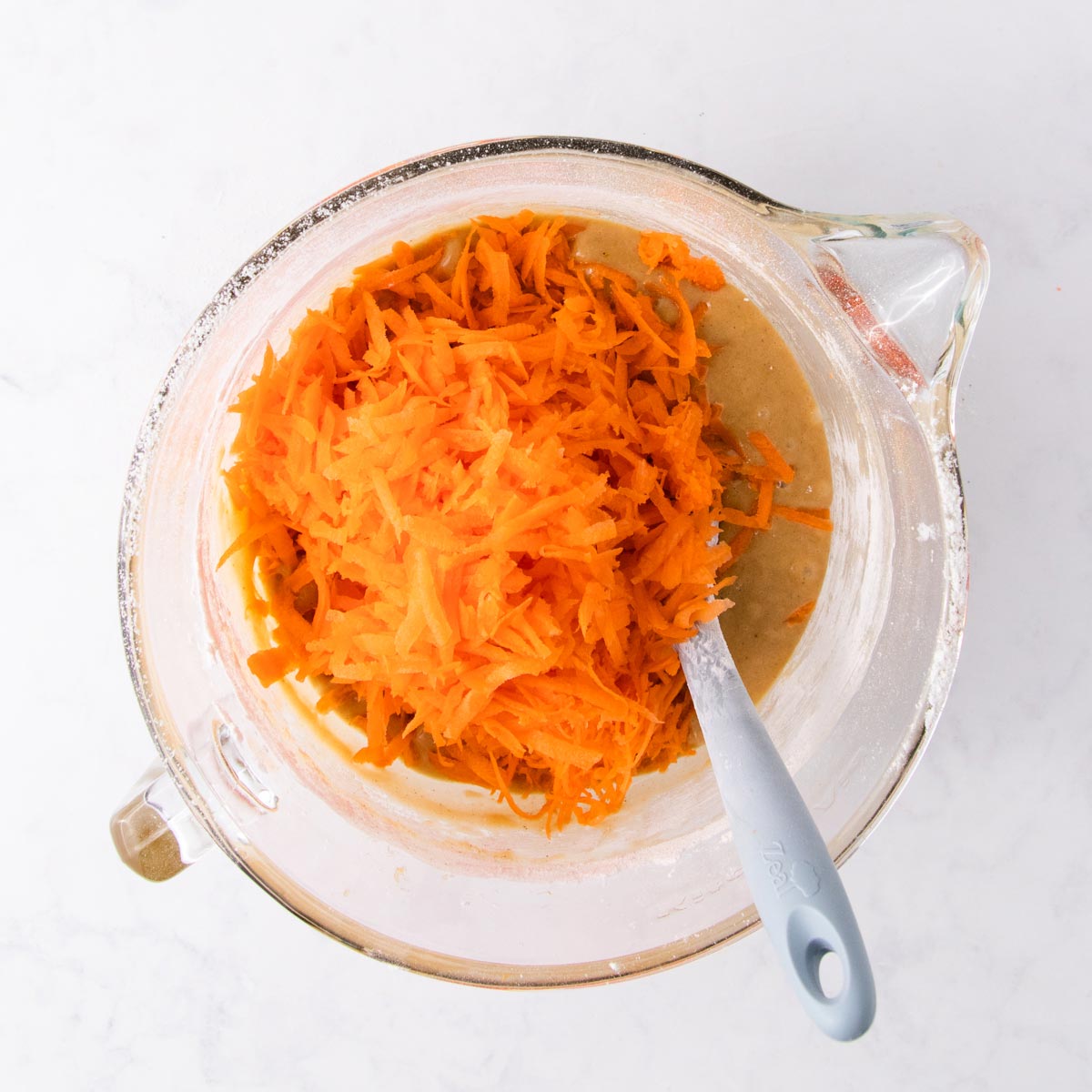 The shredded carrots being mixed into the cupcake batter.