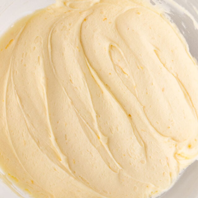 A close up of the cream cheese frosting in a glass bowl.