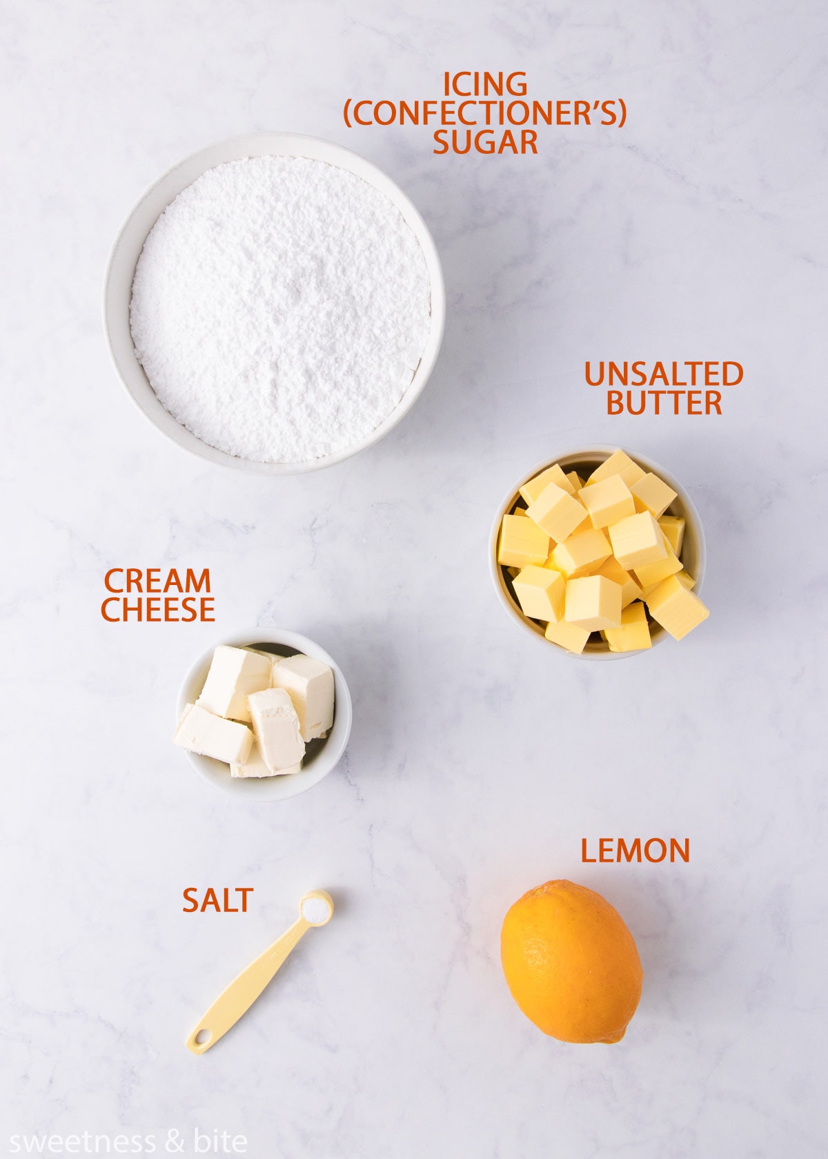 The cream cheese frosting ingredients on a grey background with orange labels.