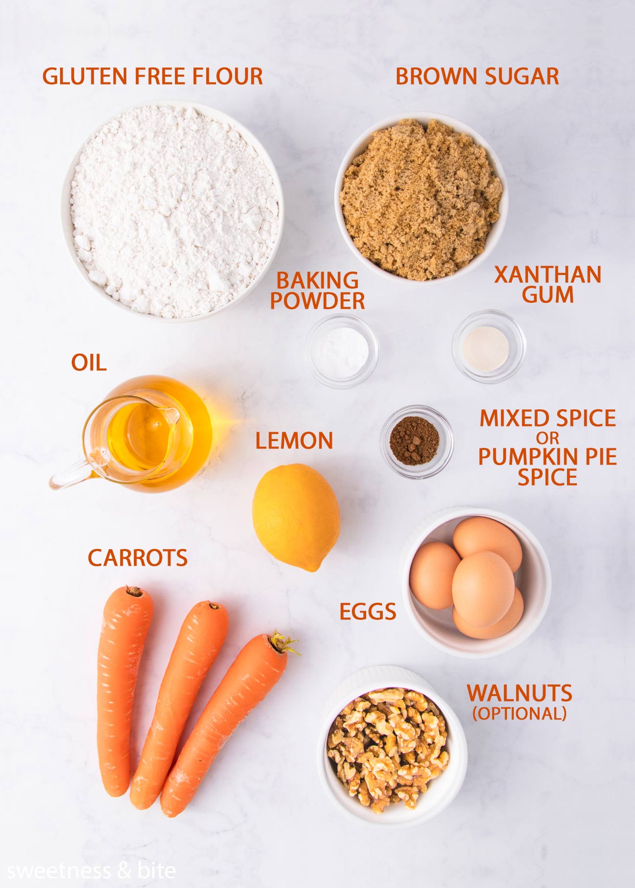 The gluten free carrot cake cupcake ingredients on a grey background with orange labels.