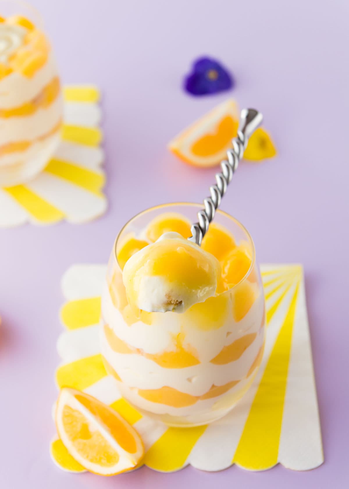 A spoonful of lemon cheesecake resting on the edge of he glass.