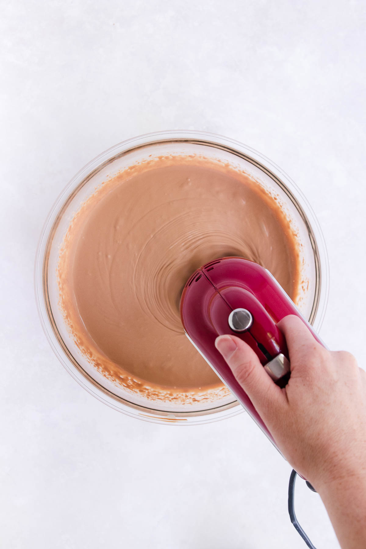 The mousse mixture being whipped with an electric hand mixer.