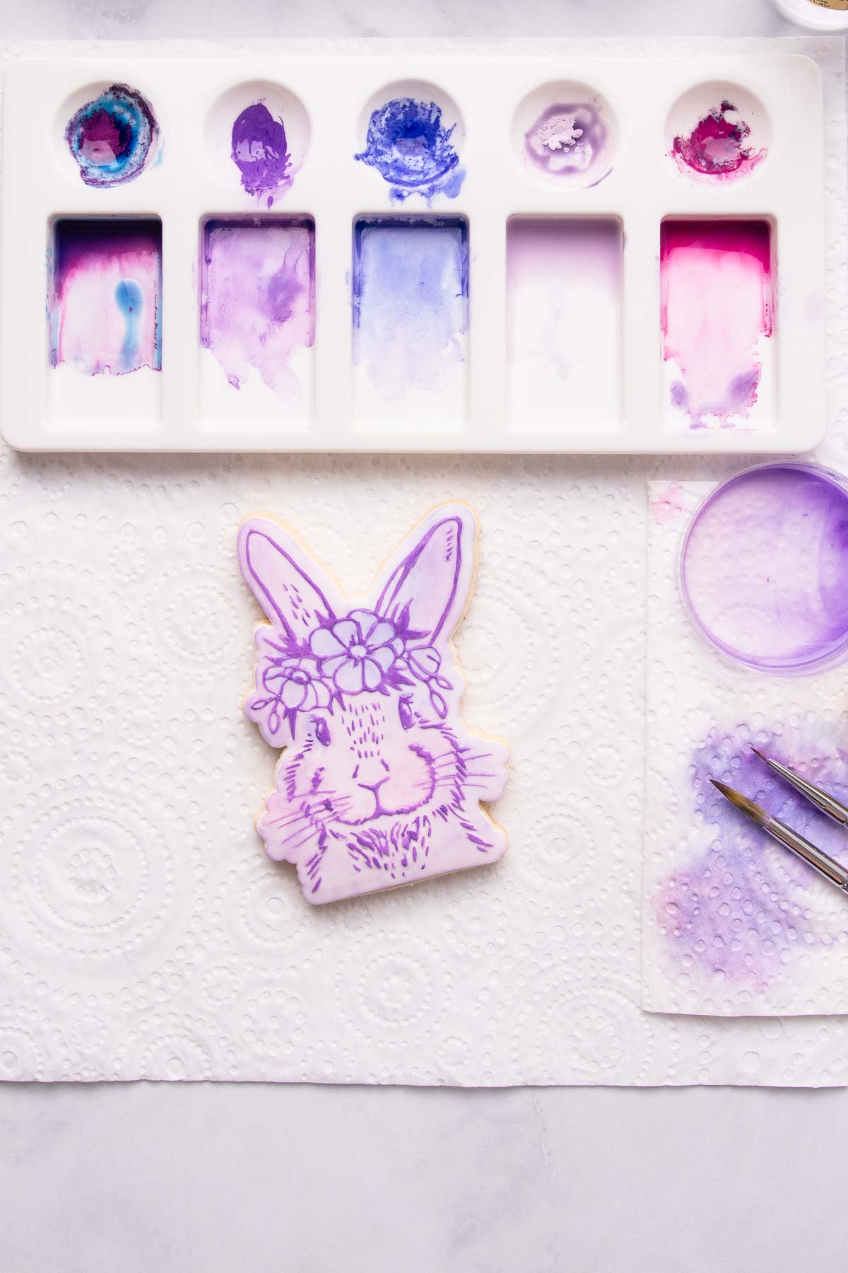 The cookie after the raised bunny design has been painted over in purple paint.
