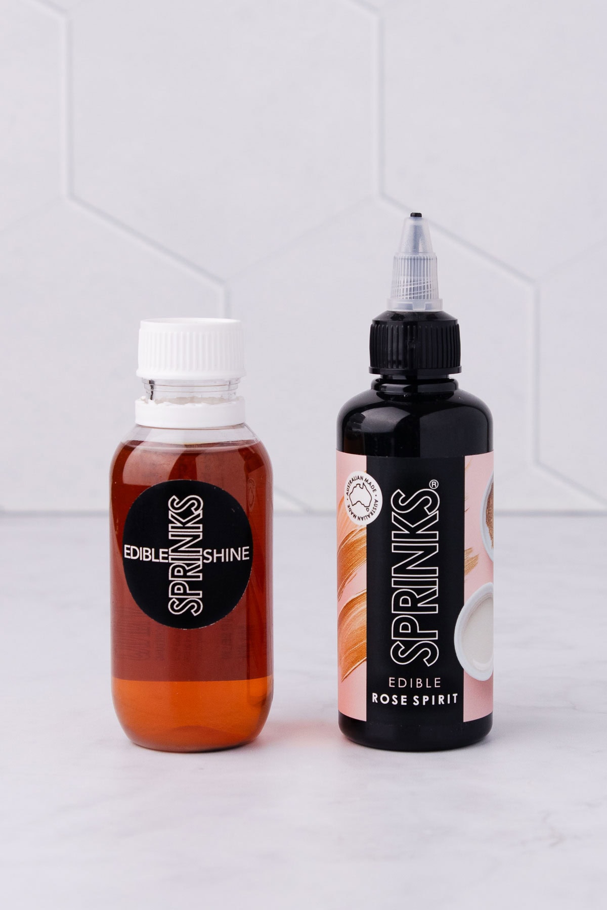 A bottle of Sprinks Confectioner's glaze and rose spirit on a grey marble background.