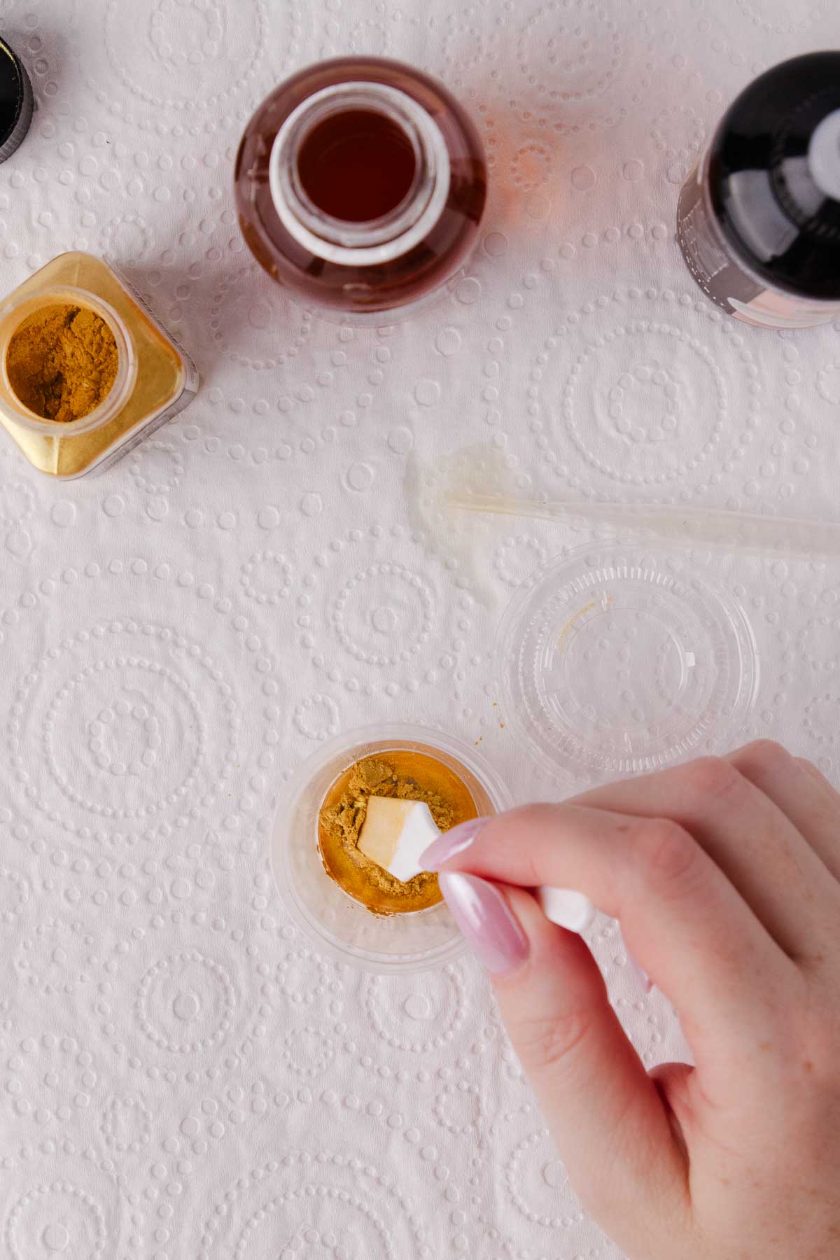 A hand gently stirring the edible gold paint. 